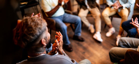Men applauding in group therapy at mental health center.