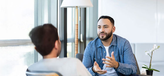 A young male therapy patient gestures as he talks about something with a female therapist.