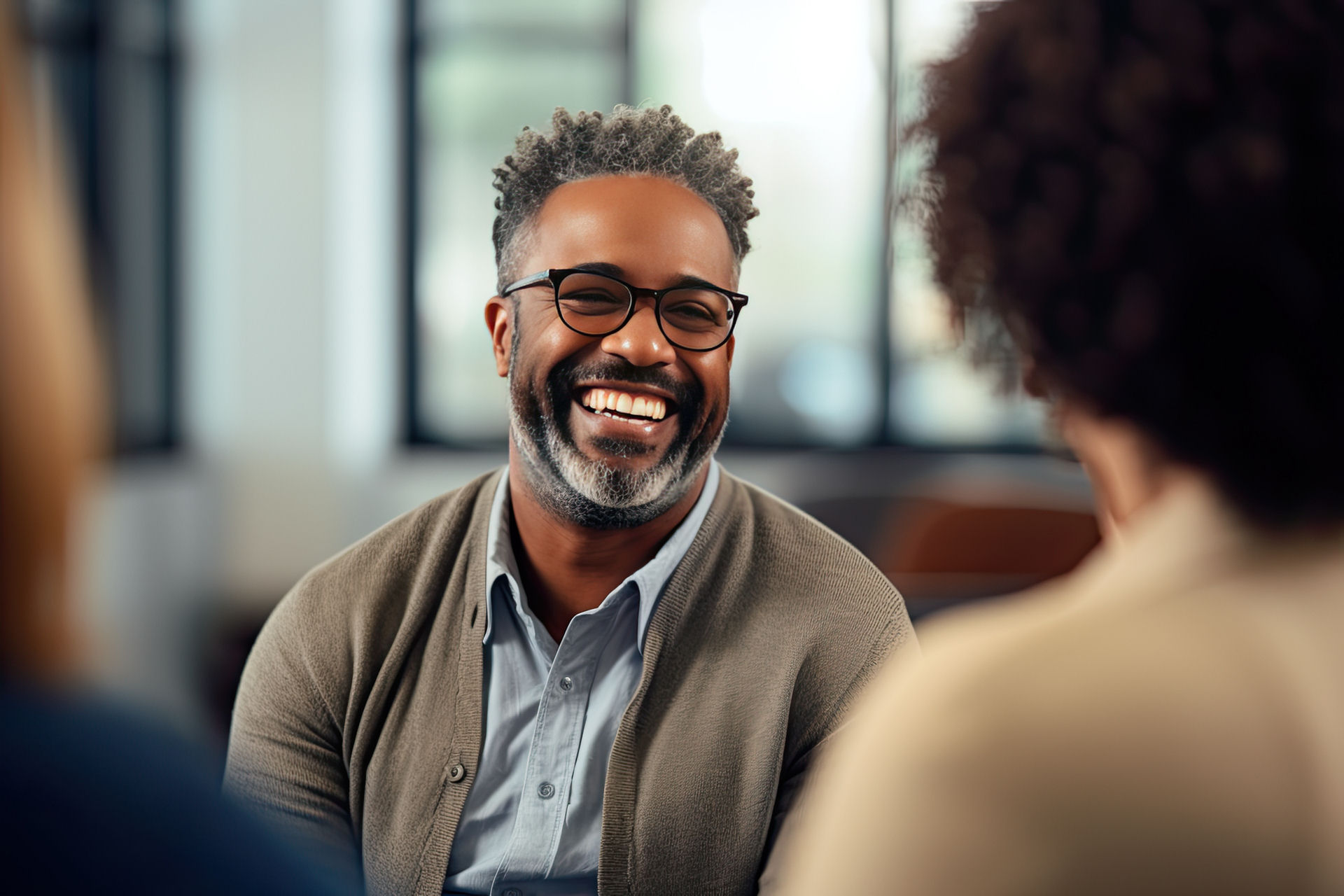 Group discussion in a bright room regarding alcohol detox. A Man smiling, looking happy and hopeful
